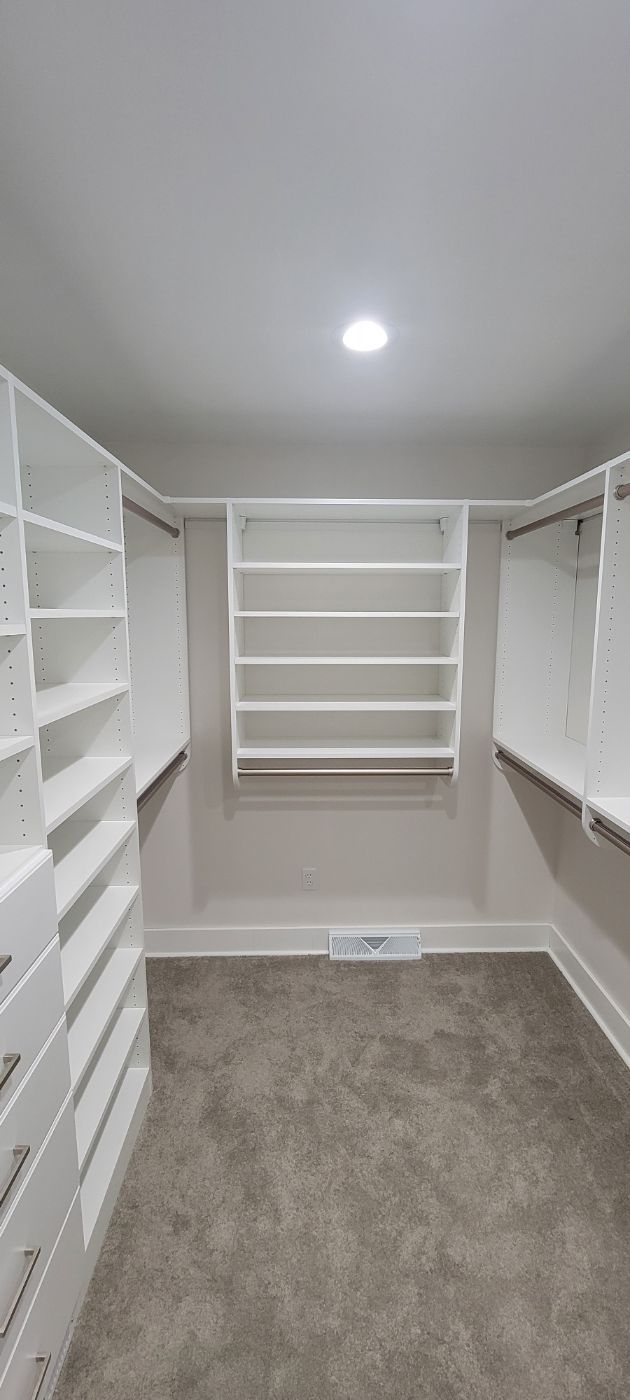 a walk in closet with lots of shelves and drawers .