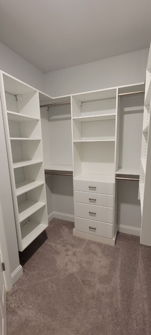 a walk in closet with lots of shelves and drawers .
