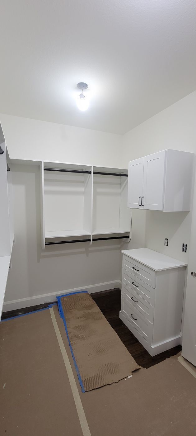 a walk in closet with white cabinets and a dresser .