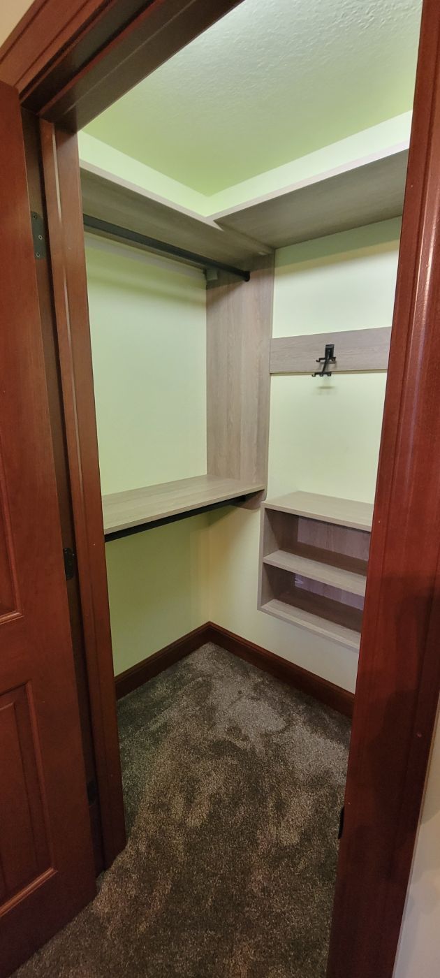 a walk in closet with a wooden door and shelves .