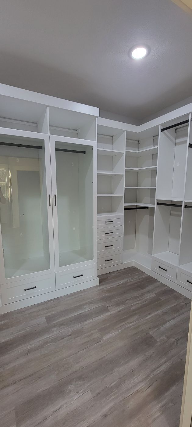 a large walk in closet with lots of shelves and drawers .
