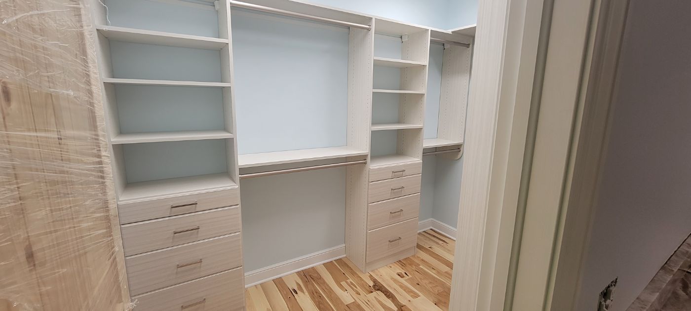 a walk in closet with lots of shelves and drawers .