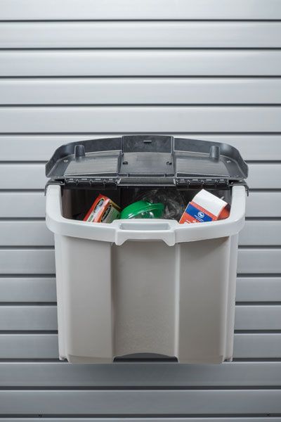 Gray wall-mounted trash bin with open lid, containing trash; set against a horizontally-lined wall.