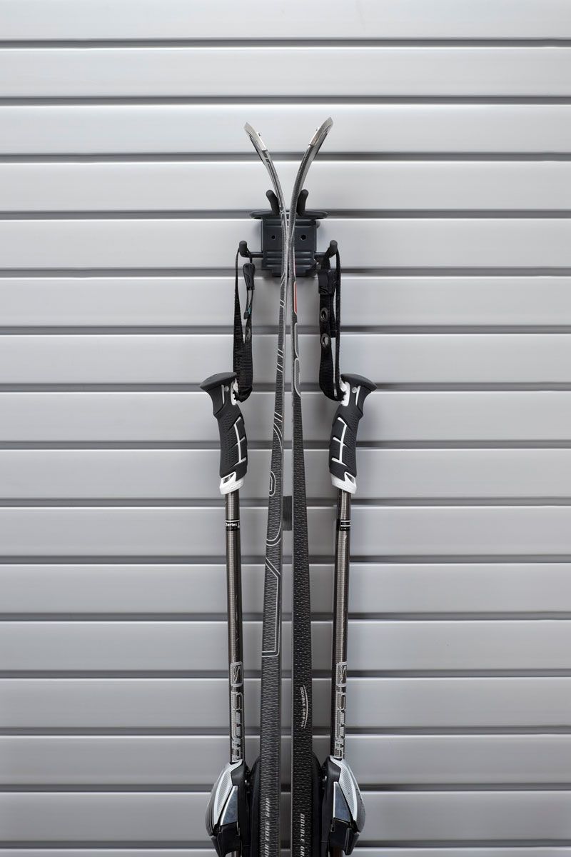 Pair of skis and poles mounted on a gray wall with horizontal lines.