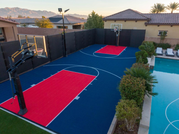 Custom backyard basketball court with blue and red playing areas beside a pool after a court installation service in San Tan Valley, AZ