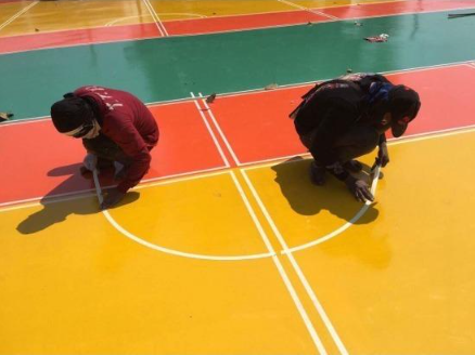 “Workers kneeling to paint detailed white court lines on a colorful sport surface during a court builder service in San Tan Valley, AZ”