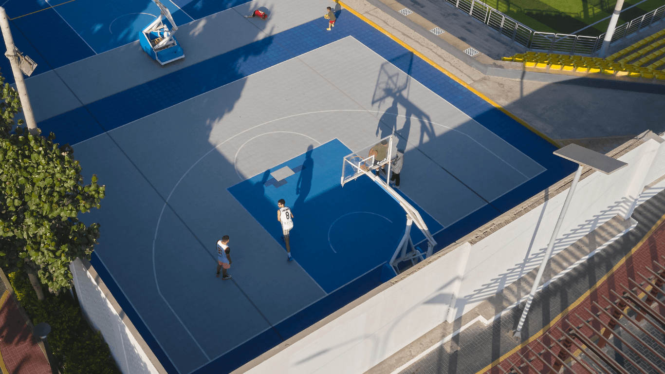 Aerial view of a modern blue backyard basketball court with players during a court installation service in San Tan Valley, AZ
