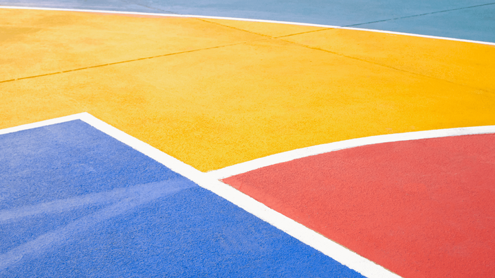 Close-up of a colorful basketball court surface with blue, yellow, and red sections during a court installation service in San Tan Valley, AZ