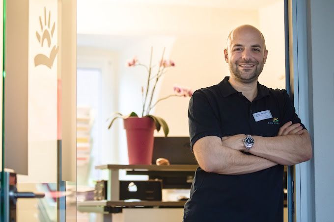 Carsten Hackamp steht mit verschränkten Armen in einem Türrahmen und lächelt.