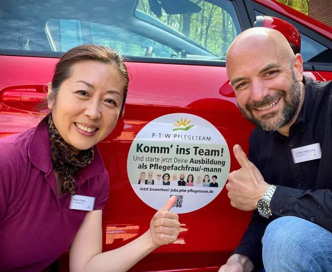 Ein Mann und eine Frau posieren für ein Foto vor einem roten Auto.