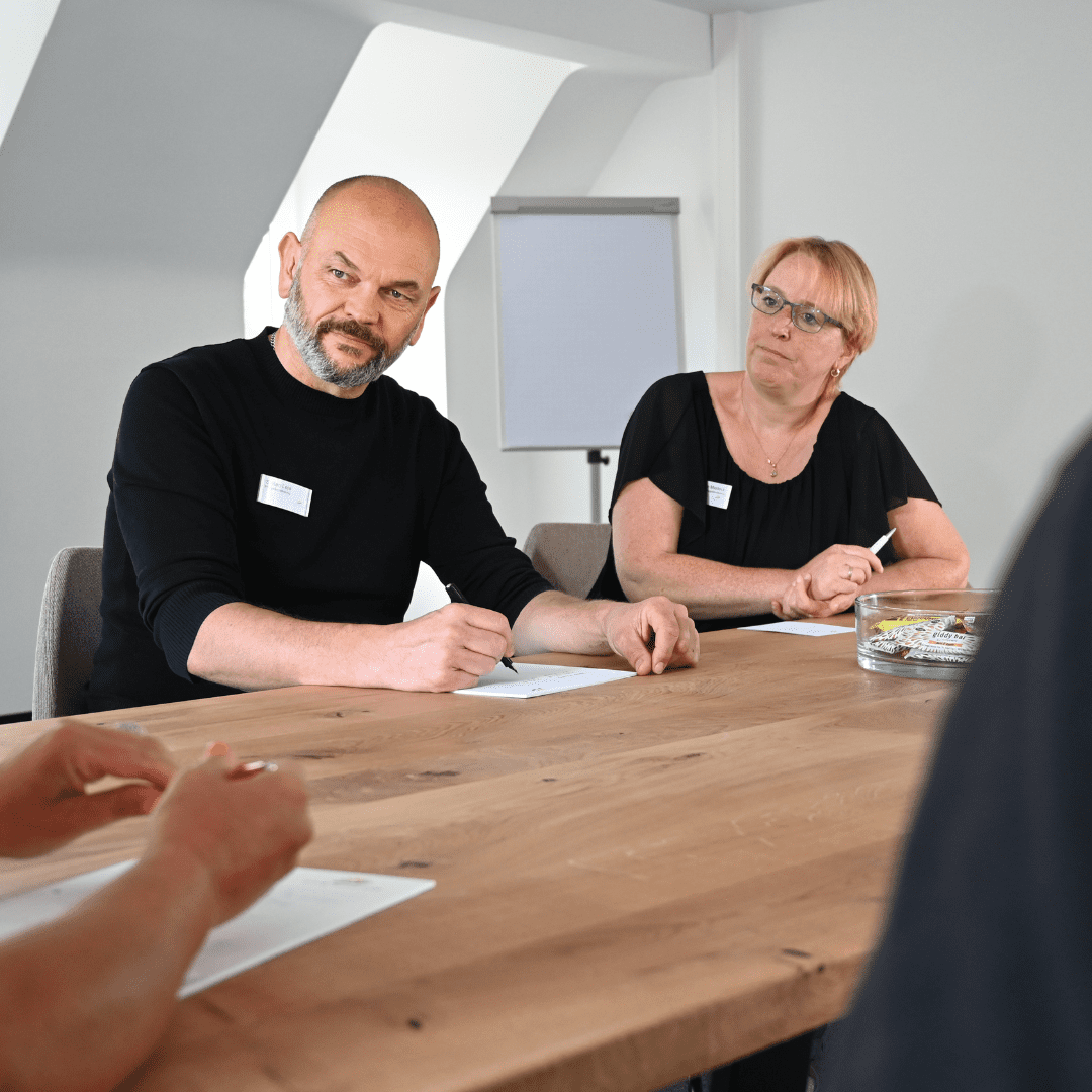 Ein Mann und eine Frau sitzen an einem Holztisch.