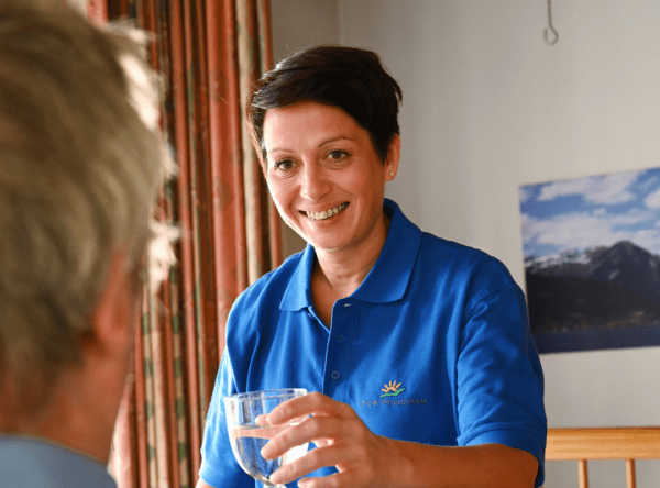 Eine Frau in einem blauen Hemd hält ein Glas Wasser