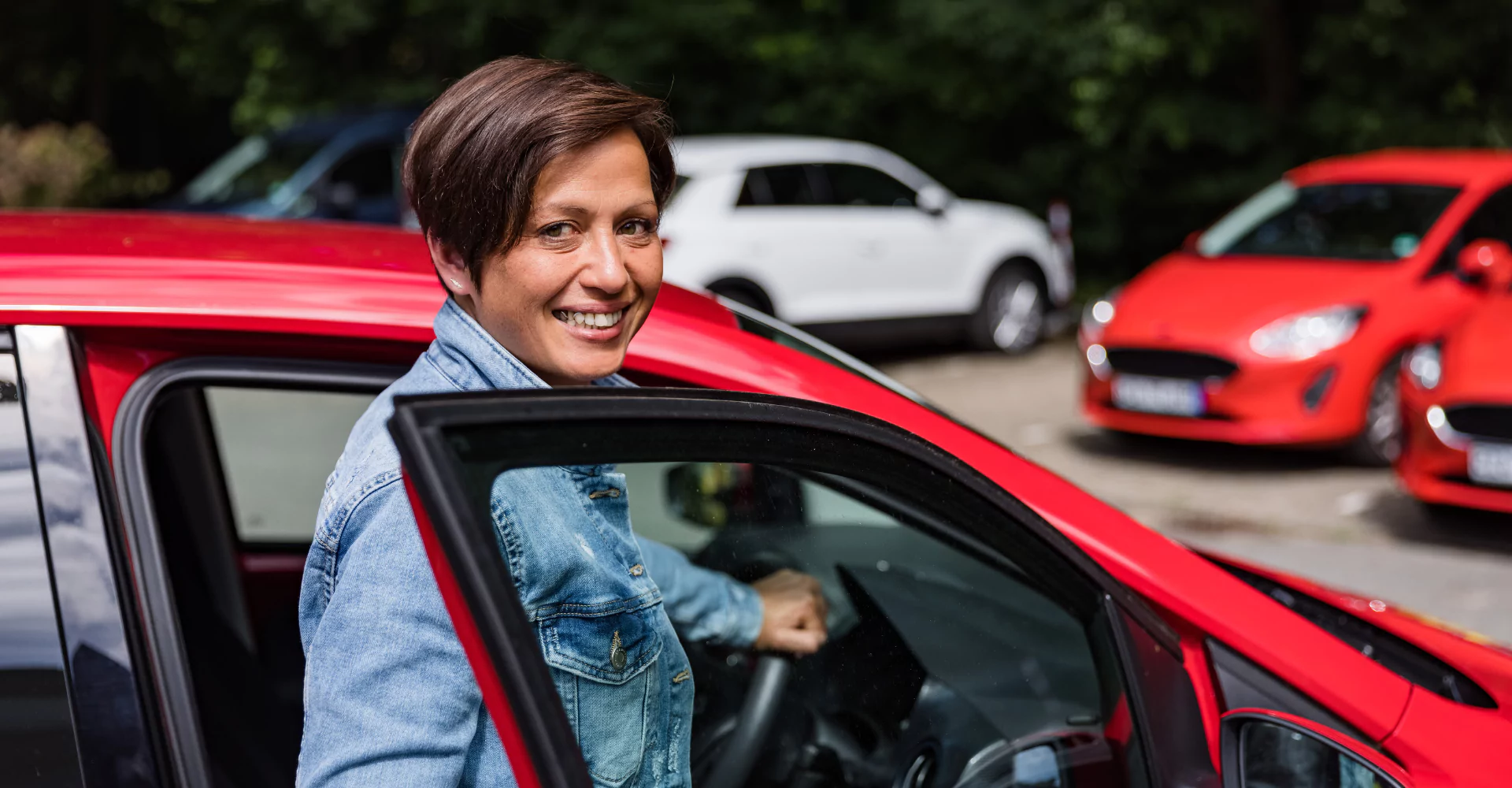 Eine Frau steigt auf einem Parkplatz aus einem roten Auto.
