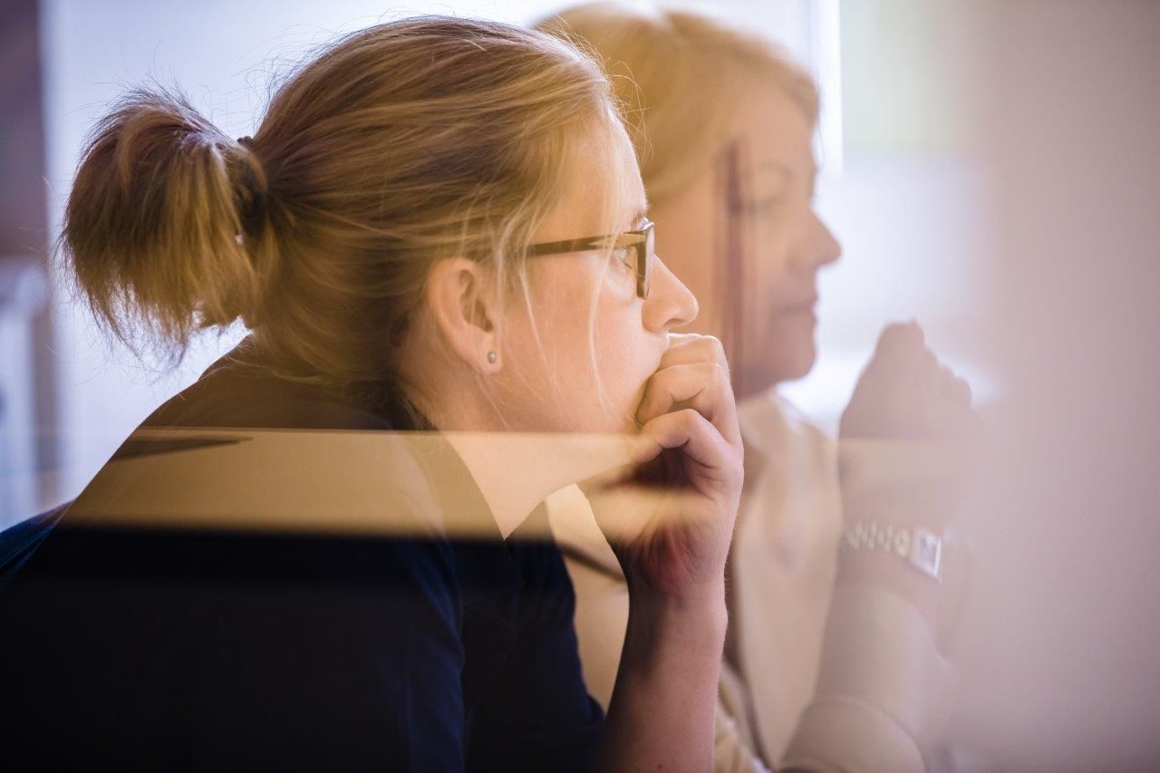 Eine Frau mit Brille sitzt vor einem Computerbildschirm.
