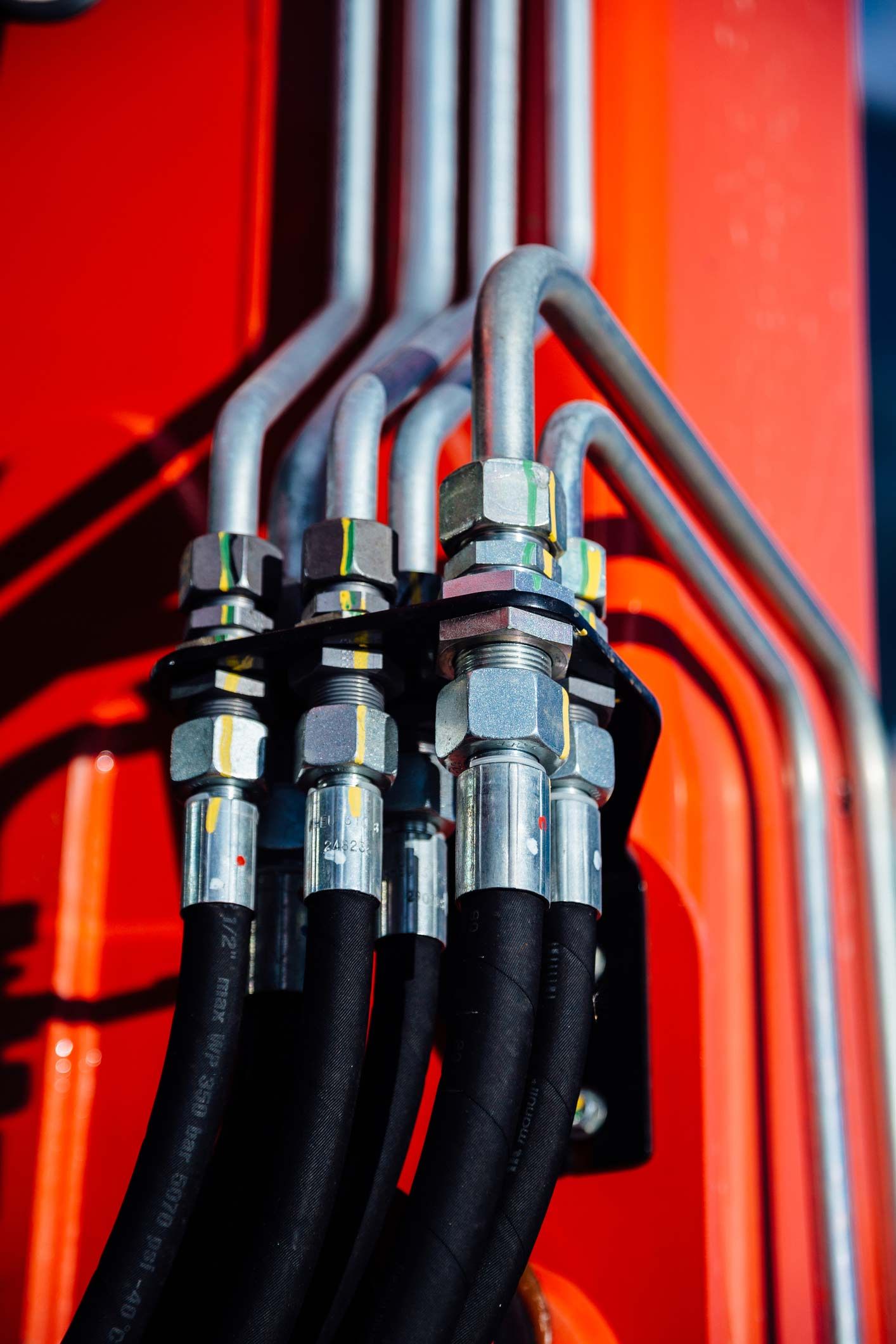 Close Up Of Hydraulic Hoses On A Red Vehicle — Lincoln, NE — Central States Hydraulic Services Hydraulic hoses and metal tubes connected to a red machine.