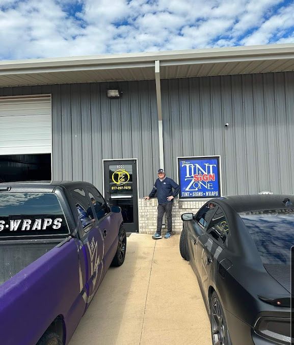 A man stands in front of a building with a sign that says tint zone