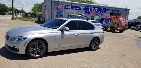 A silver car is parked in front of a building.