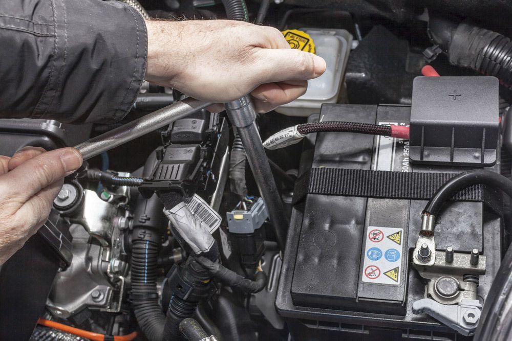 Person Uses a Wrench to Work on a Car Engine Near a Battery — A1 Safety Certificates & Repairs in Gordonvale, QLD