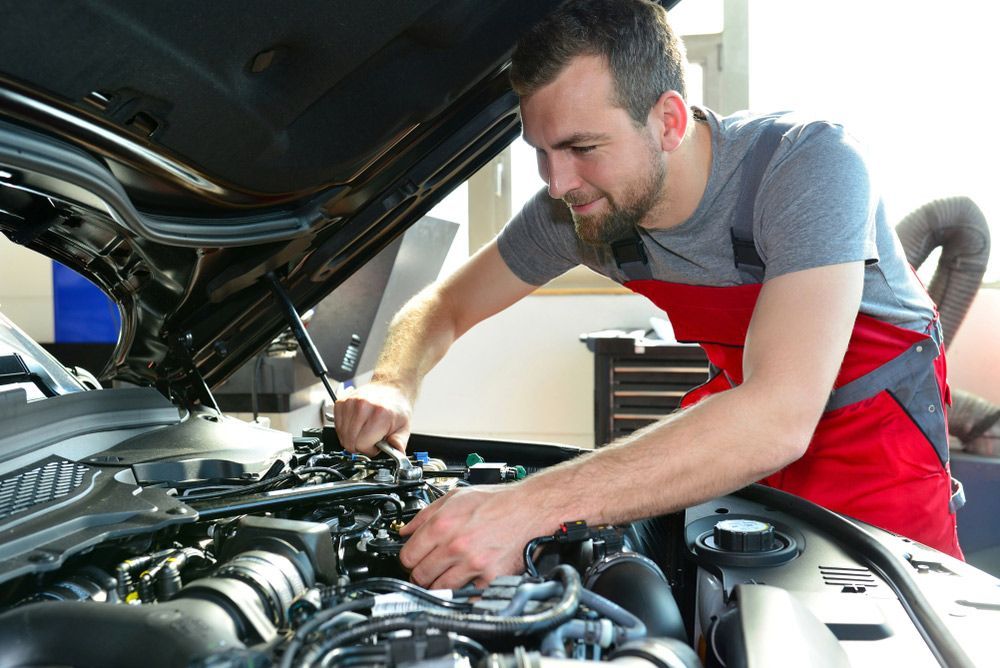 Mechanic Working on a Car Engine With the Hood Open in a Garage — A1 Safety Certificates & Repairs in Gordonvale, QLD