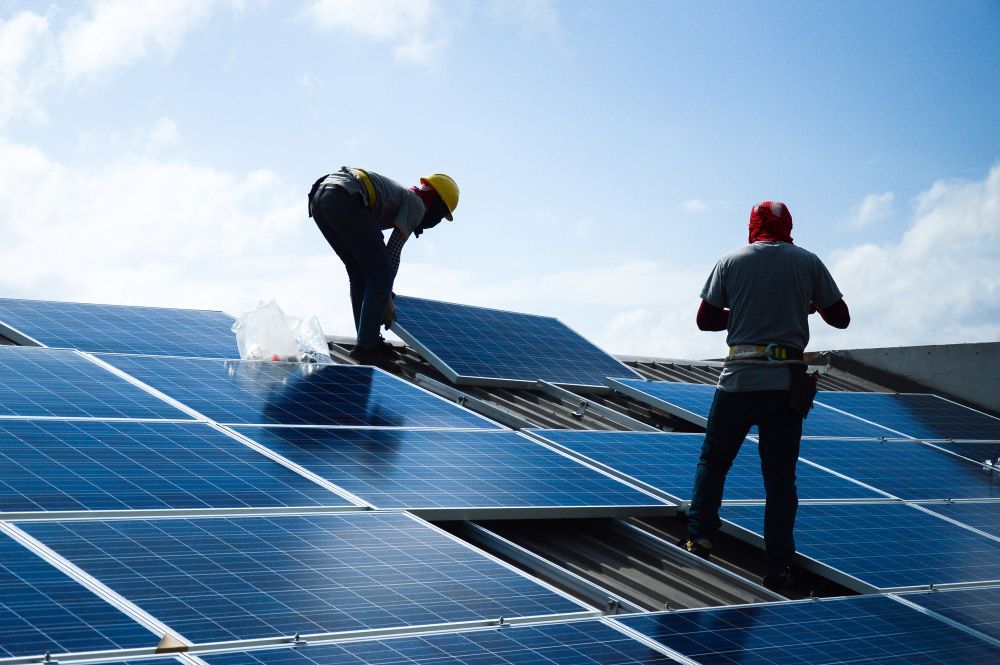 Two Men in Uniform Are Installing Solar Panels on A Roof — Ryde Energy in Brown Plains, QLD