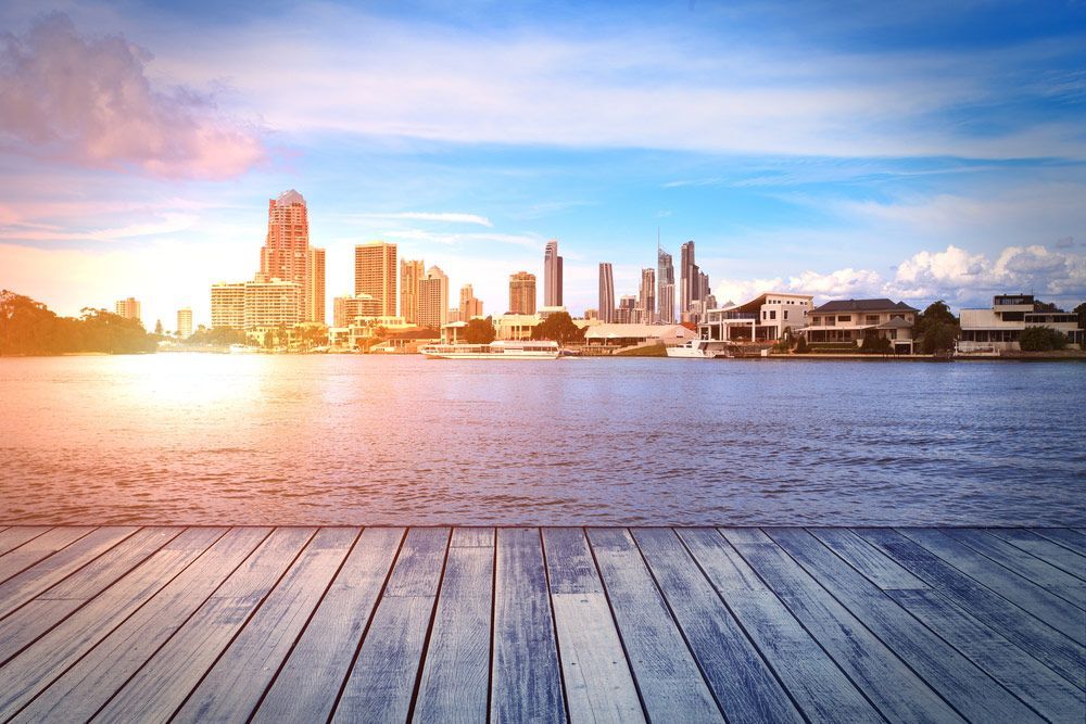 A Wooden Pier Overlooking a Body of Water with A City Skyline in The Background — Ryde Energy in Gold Coast, QLD