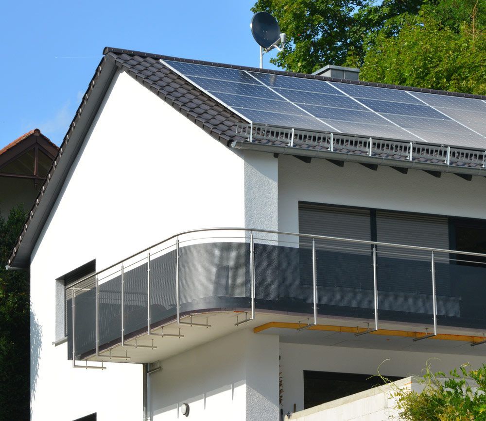 A White House with A Balcony and Solar Panels on The Roof — Ryde Energy in Browns Plains, QLD
