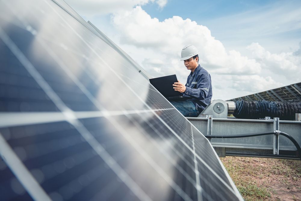 A Man Is Sitting on Top of A Solar Panel Using a Laptop — Ryde Energy in Browns Plains, QLD