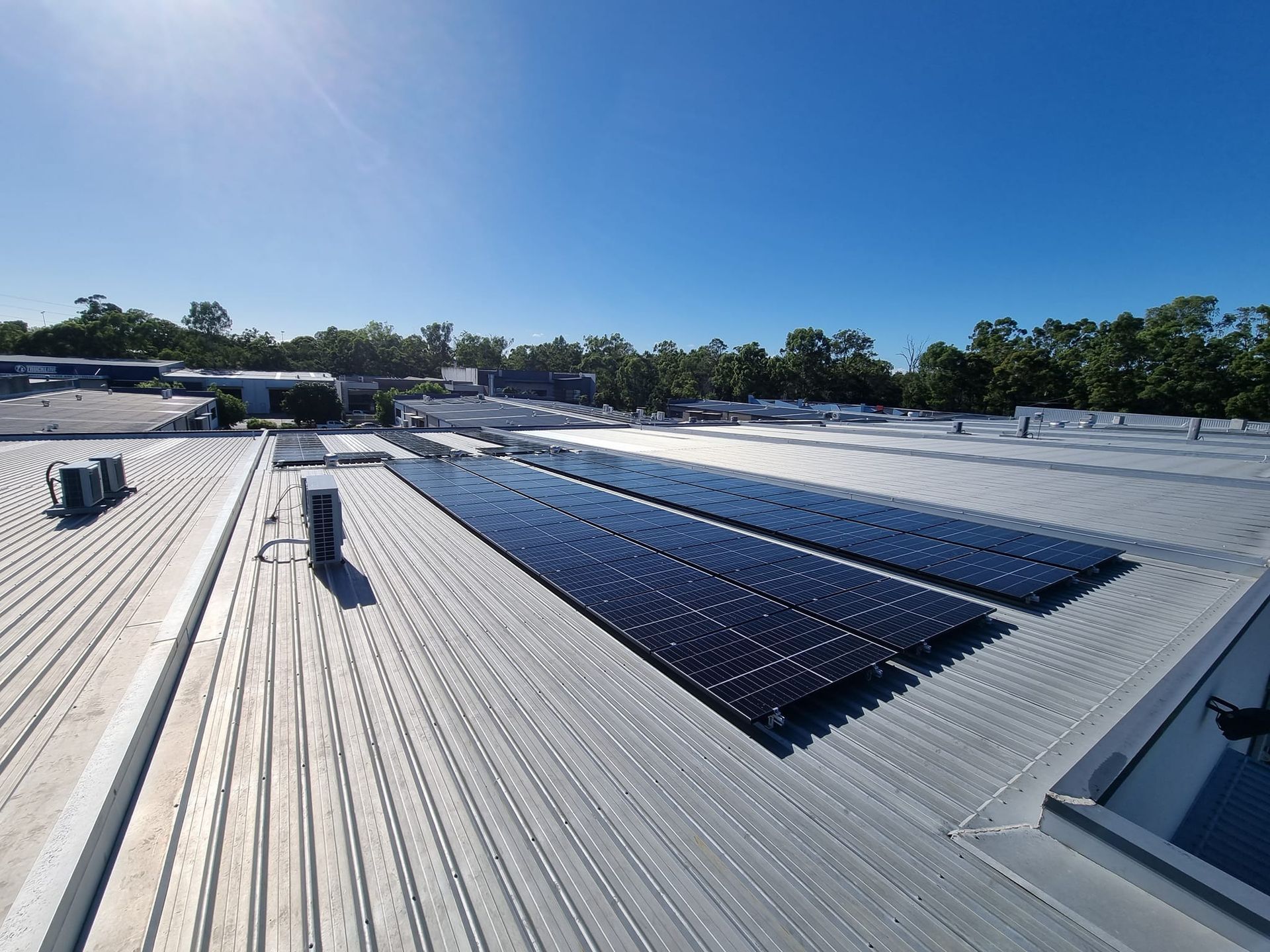 Rooftop Solar Panels on a White Metal Roof Under a Clear Blue Sky — Ryde Energy in Browns Plains, QLD