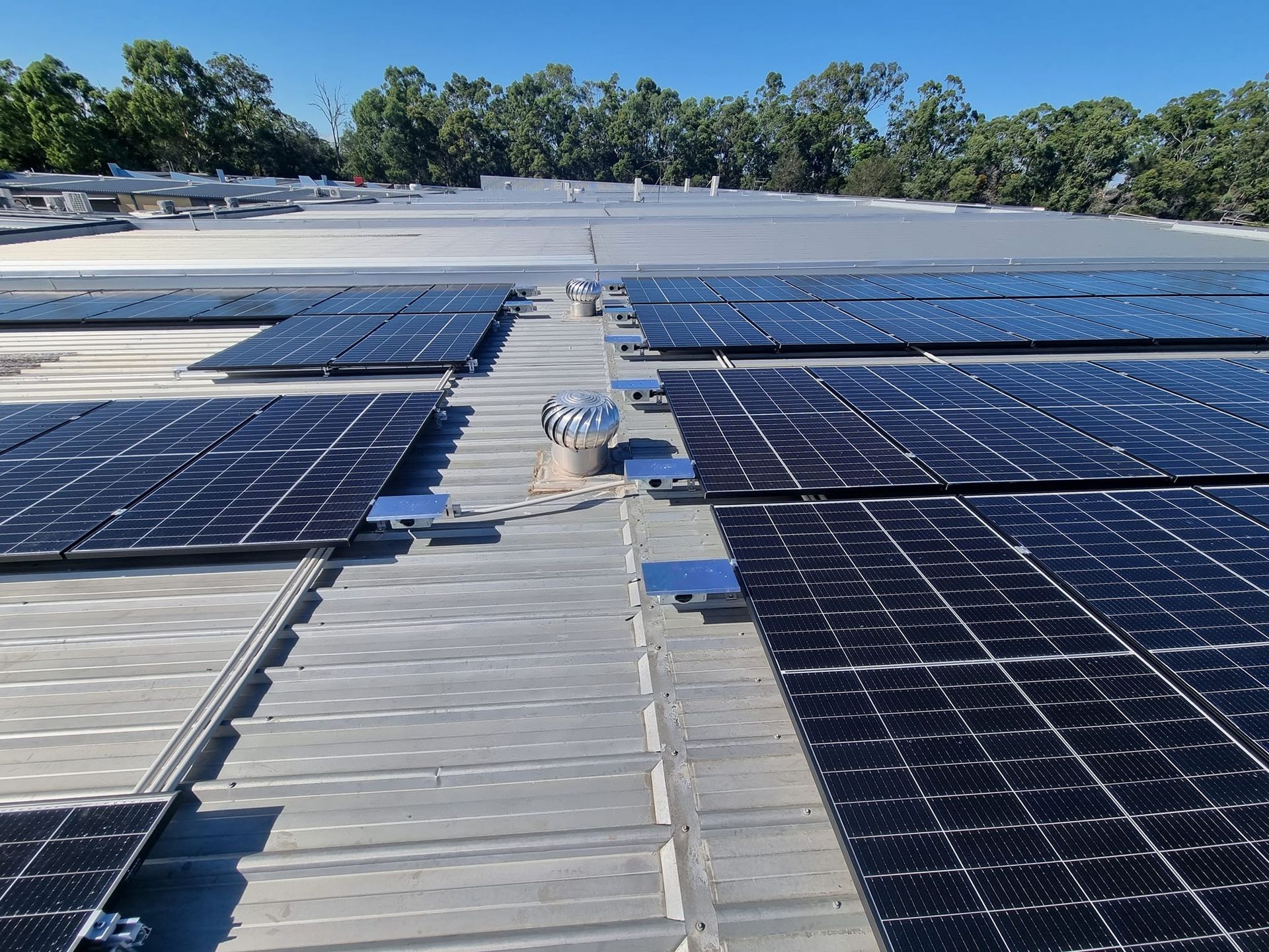 Solar Panels Installed Across a Flat Rooftop Under a Clear Blue Sky — Ryde Energy in Browns Plains, QLD