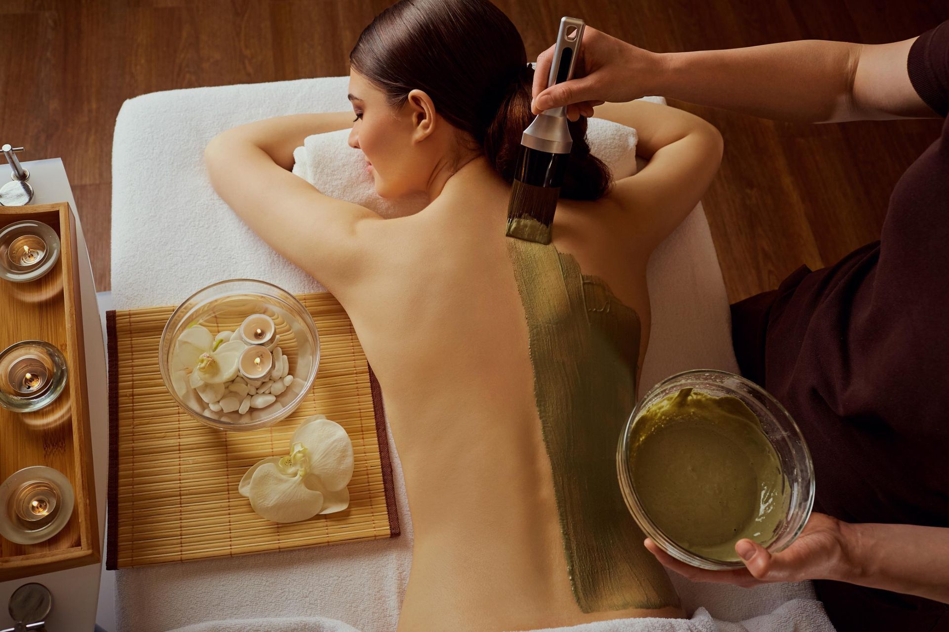 A woman is getting a clay treatment on her back at a spa.