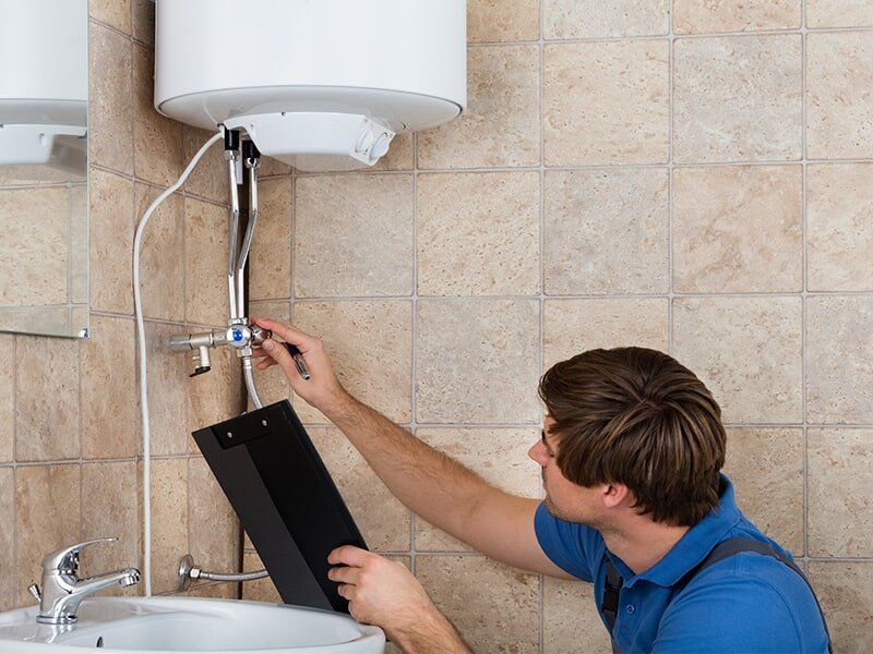 Plumber Inspecting a Hot Water System — Hot Water System Installation in Moranbah, QLD Plumber Inspecting a Hot Water System — Hot Water System Installation in Moranbah, QLD