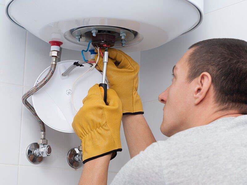 Plumber Fixing a Hot Water System — Hot Water System Installation in Moranbah, QLD Plumber Fixing a Hot Water System — Hot Water System Installation in Moranbah, QLD