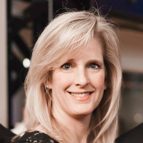 A woman wearing hoop earrings and a white shirt is smiling for the camera.