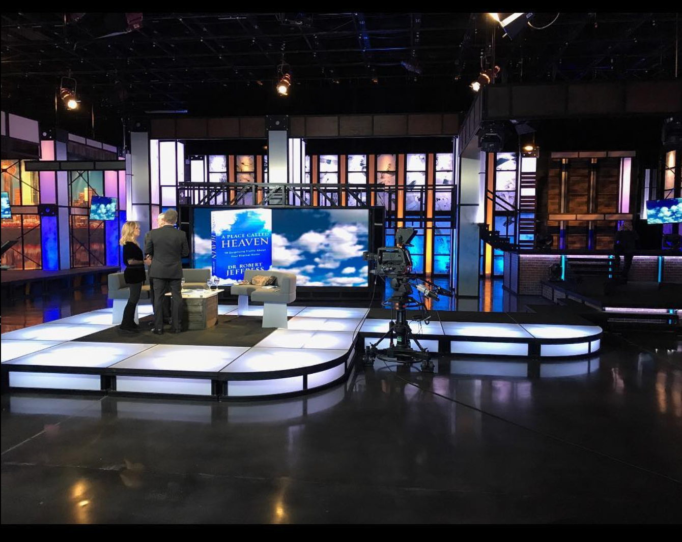 A television studio with a large screens on a white platform