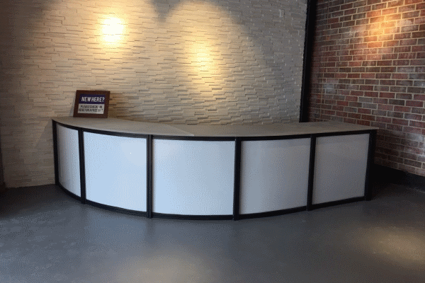 A curved white counter in front of a brick wall.