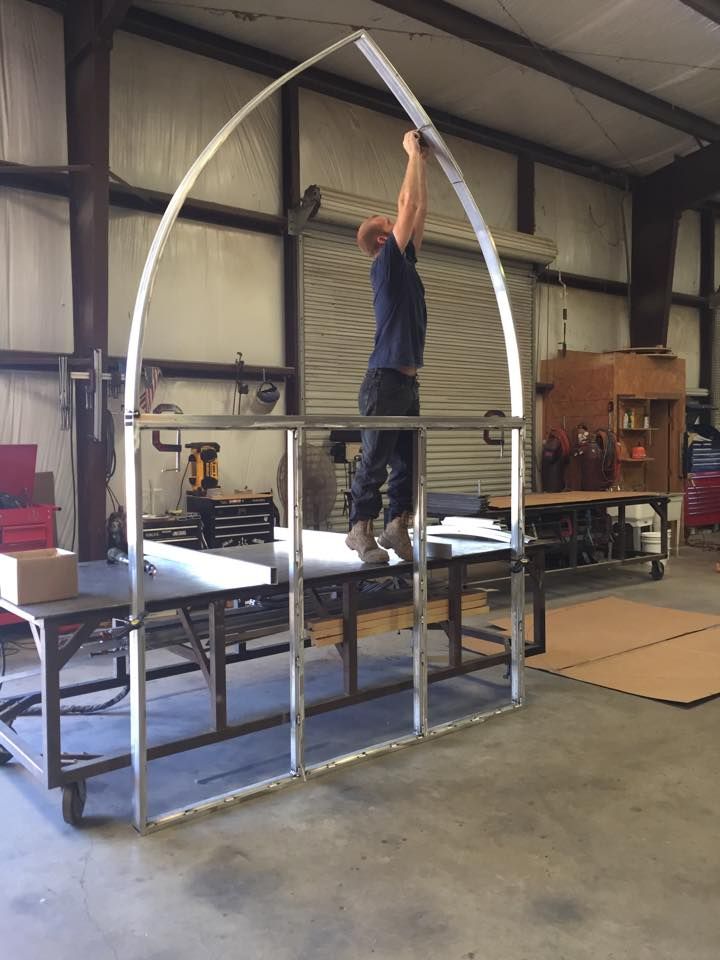 A man is working on a metal structure in a warehouse.