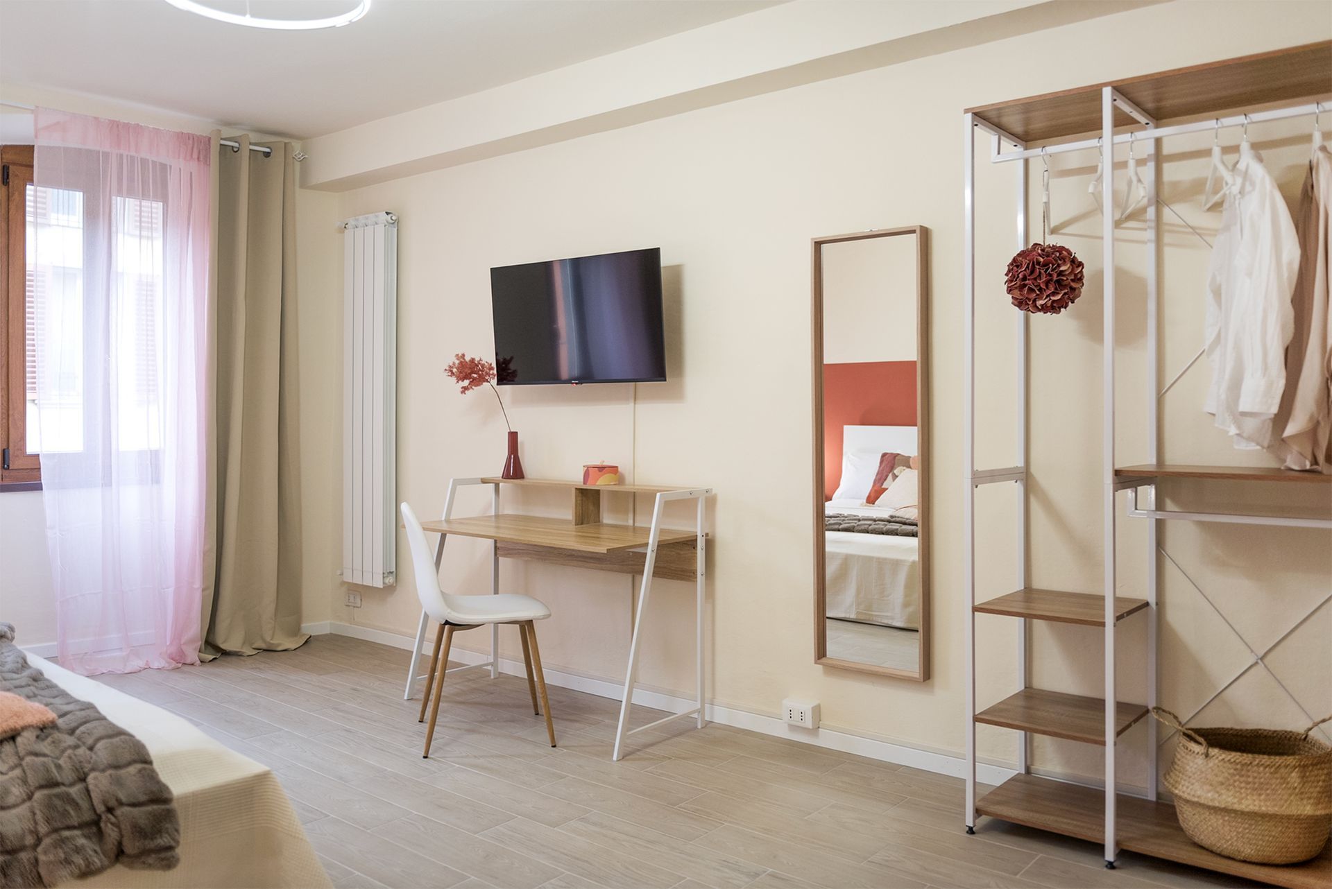 Desk, wall mounted TV and open wardrobe.