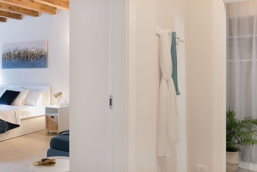 Scorcio luminoso attraverso una porta che mostra una camera da letto matrimoniale con dettagli blu.
