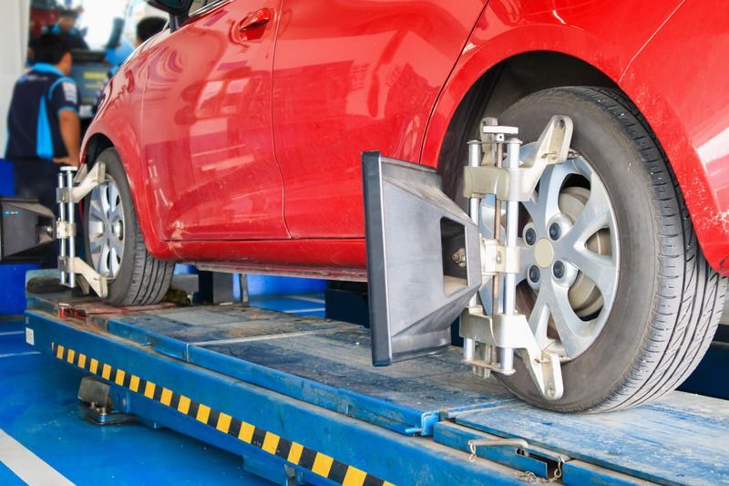 A red car is being aligned with a machine in a garage.
