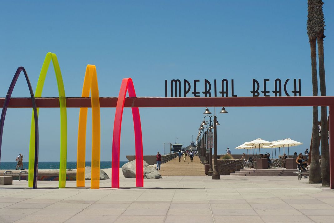 people are walking on the pier at imperial beach