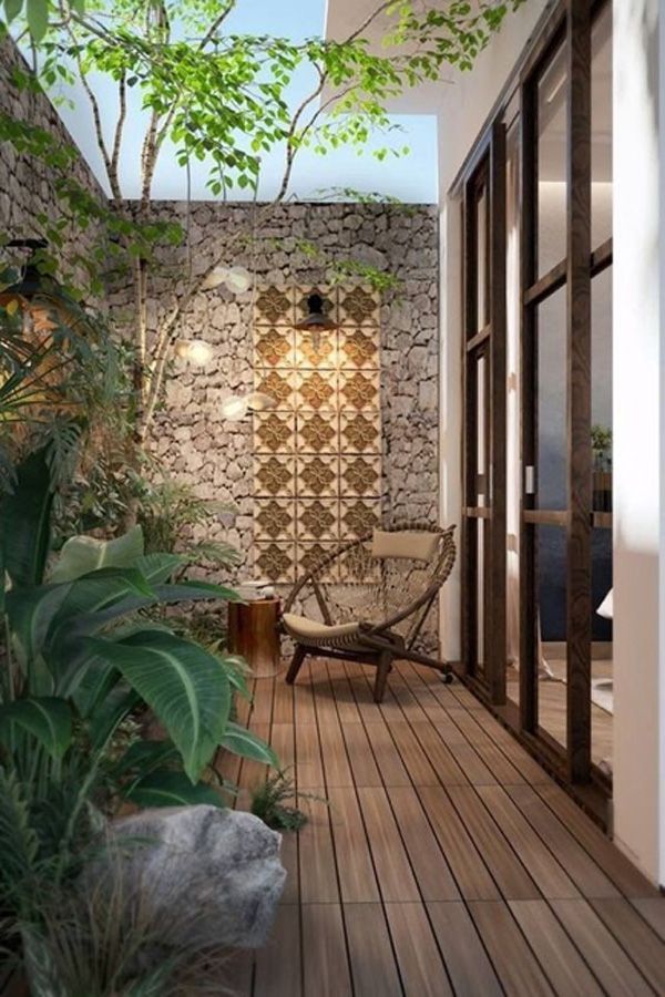 Small outdoor wooden patio with light hanging from stone wall