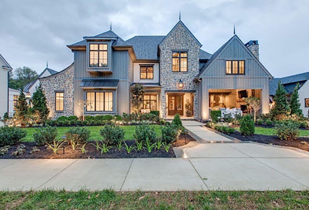 A 2-story stone French-country home with beautiful exterior lighting