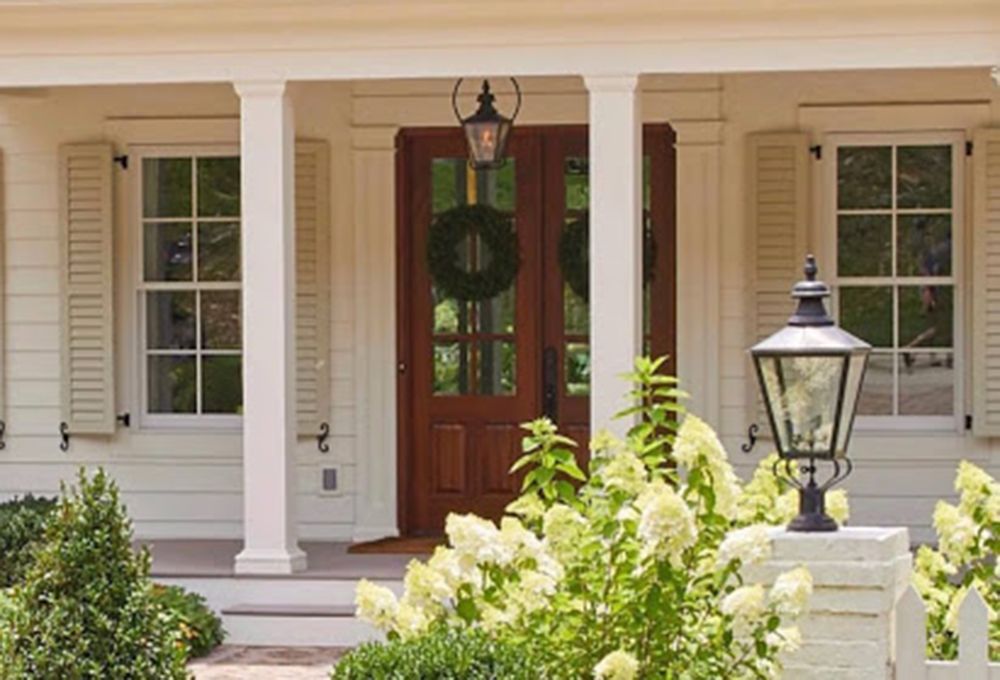 A white house with a light fixture hanging about the front door