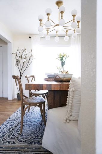 Gold and white chandelier hanging over natural wood table