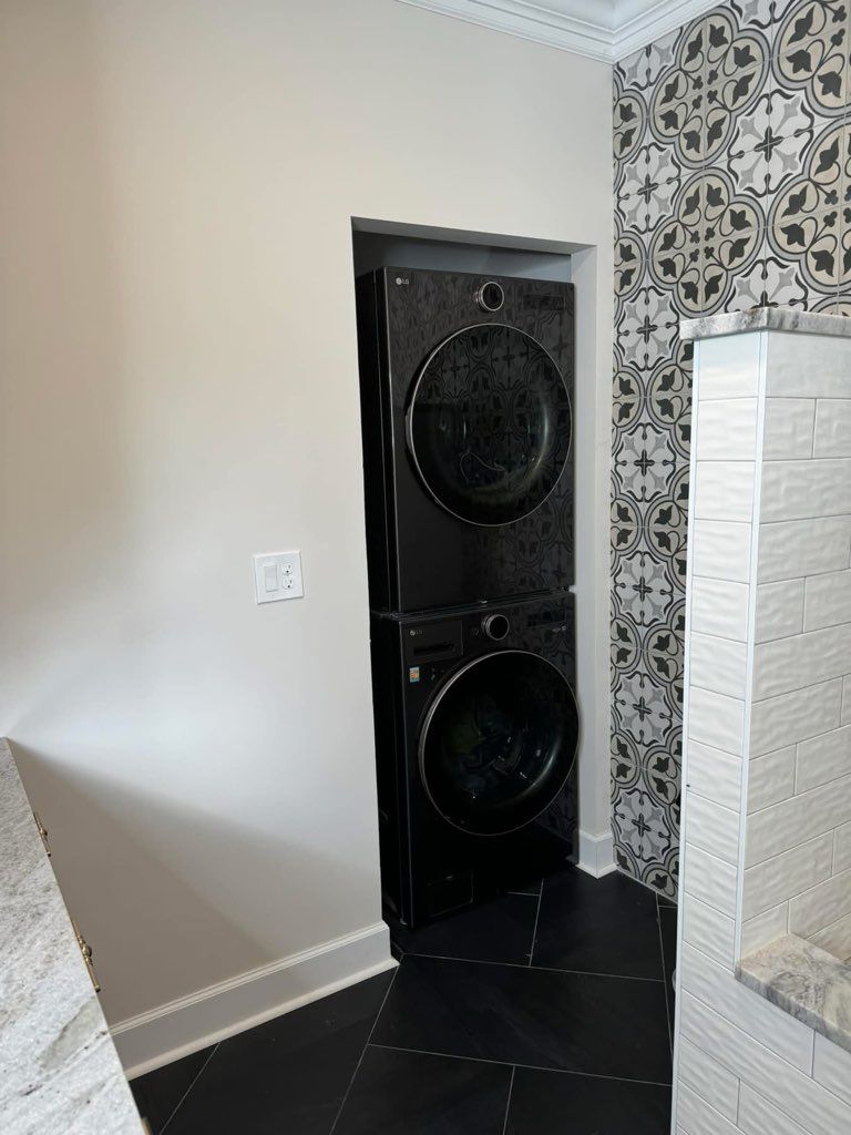 Built-in black speaker cabinet in a tiled corner next to a patterned wall and white fireplace surround