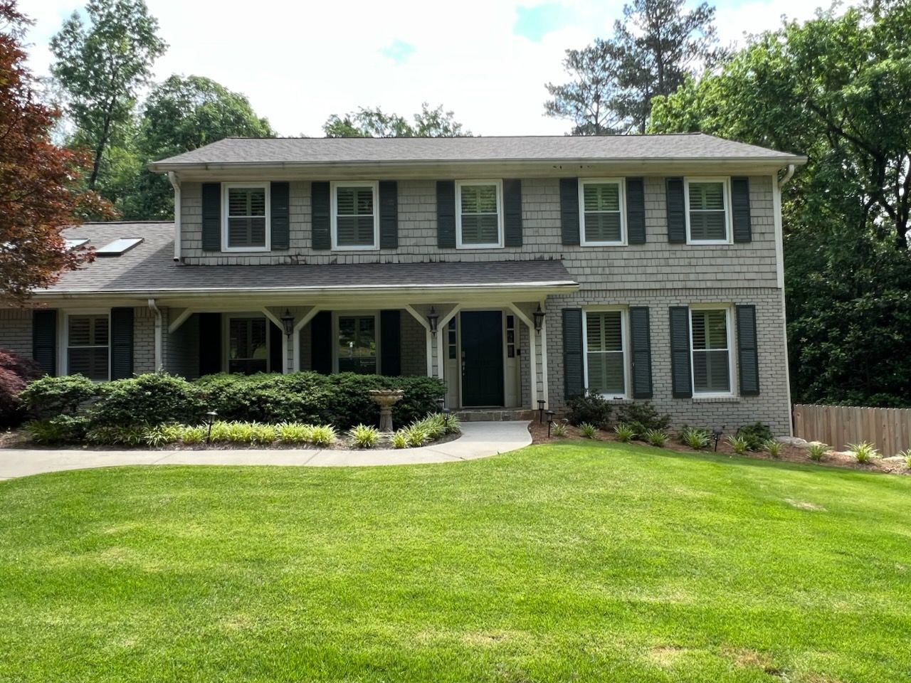 Two-story gray house with white trim, front porch, and a large green lawn