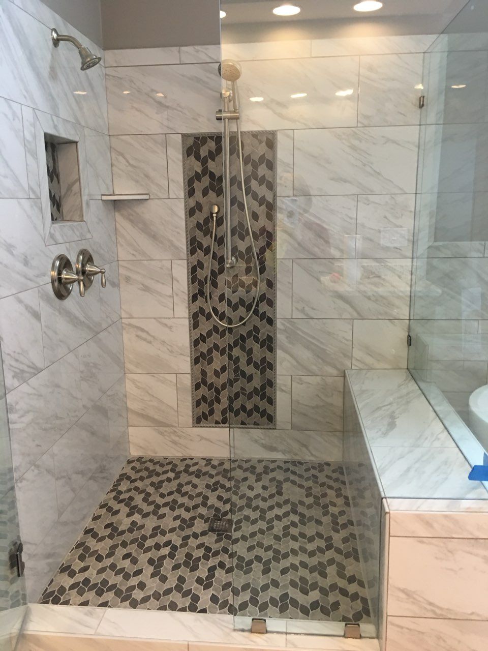 A bathroom with white cabinets , a sink , a mirror and towels.