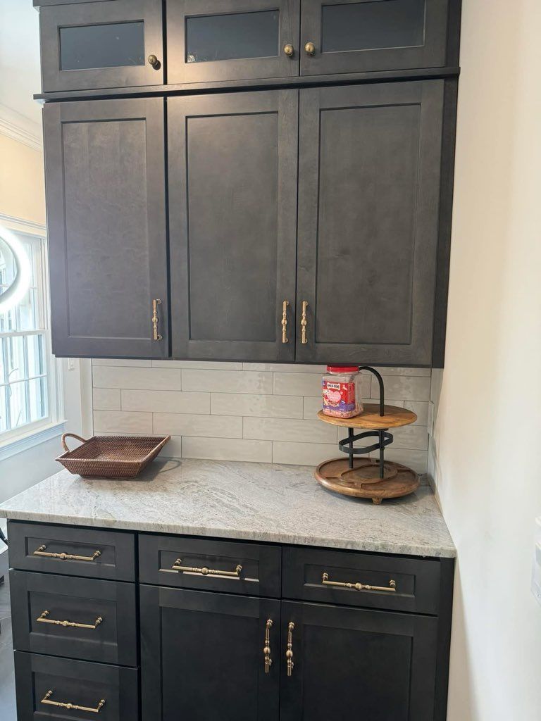 Dark gray kitchen cabinets with marble countertop and white subway tile backsplash.