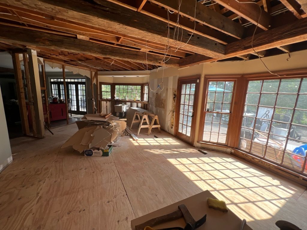 Empty room with light blue walls, wood floors, red trim, and a raised window seat.