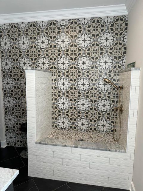 Patterned tiled shower niche with built-in bench and light stone trim in a bathroom